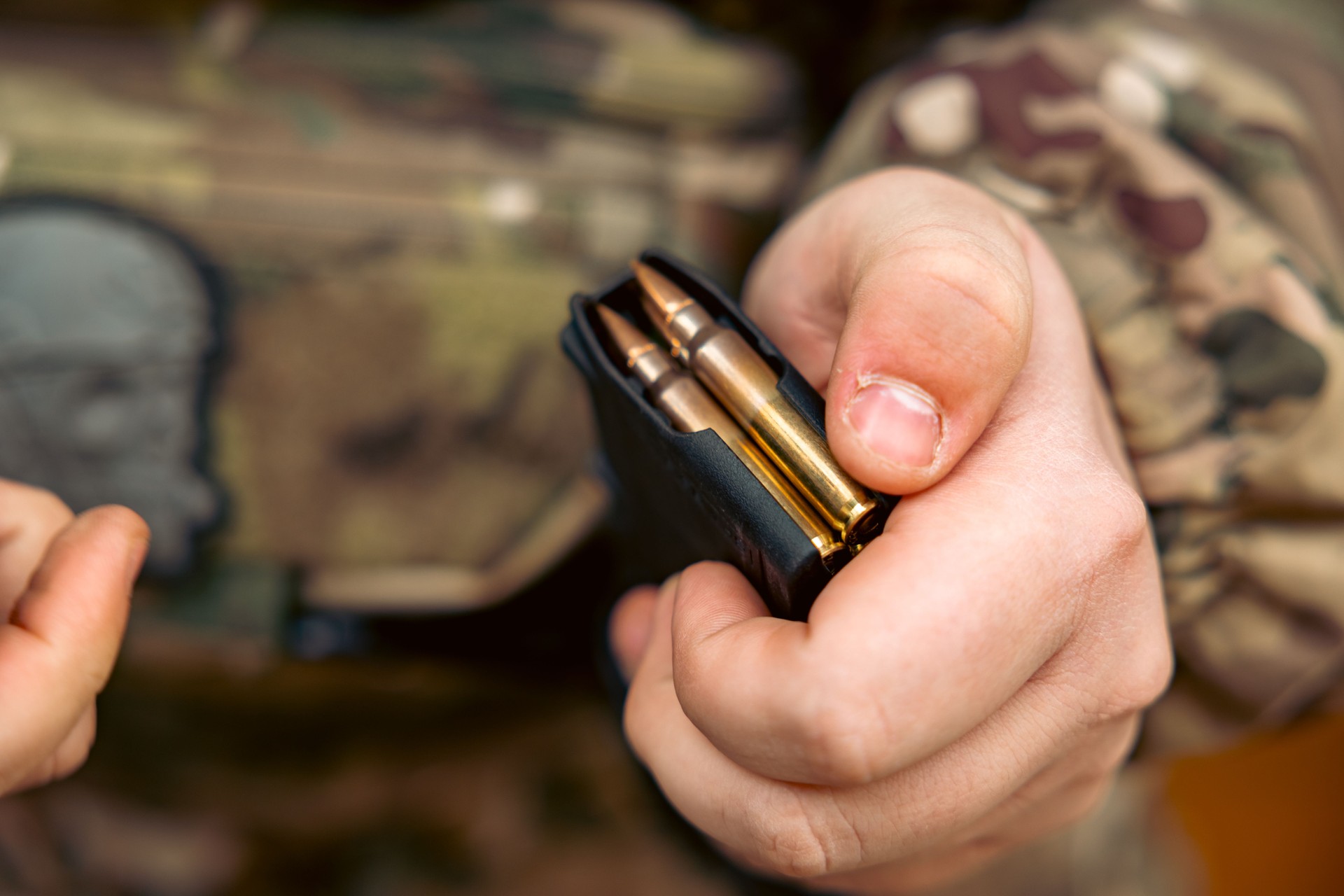 Firearms, AK magazine with 7.62x39mm cartridges in a man's hand.